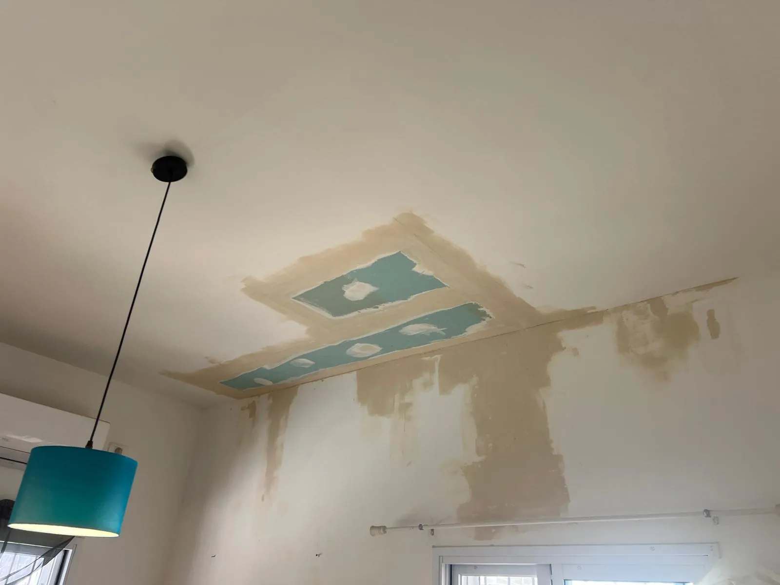 טלאים מלוח גבס ירוק עם רשת שפכטל סוגרים פתח בתקרה מעל קיר עם כתמי רטיבות