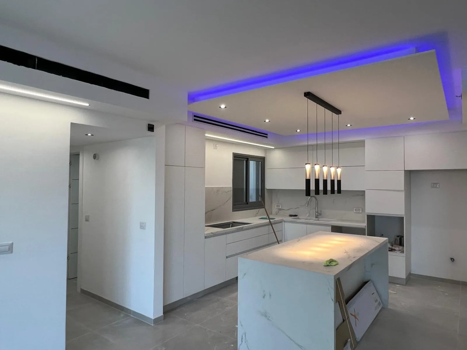 מטבח עם קופסת גבס מעל אי המטבח ותאורת LED נסתרת בגוון כחול