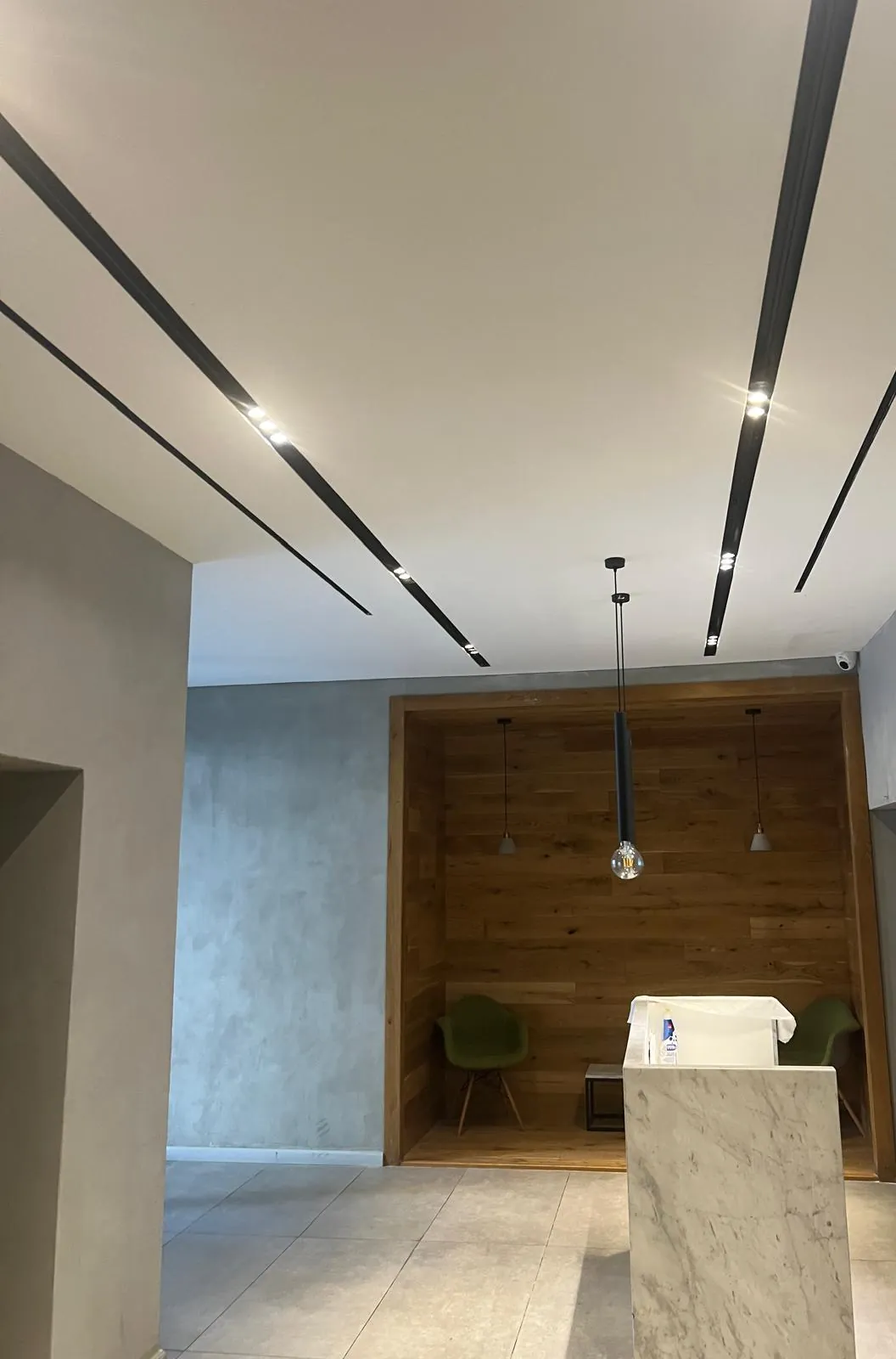 תקרת גבס לבנה בלובי עם פסי תאורה ליניארית שחורים חקוקים לתוך התקרה