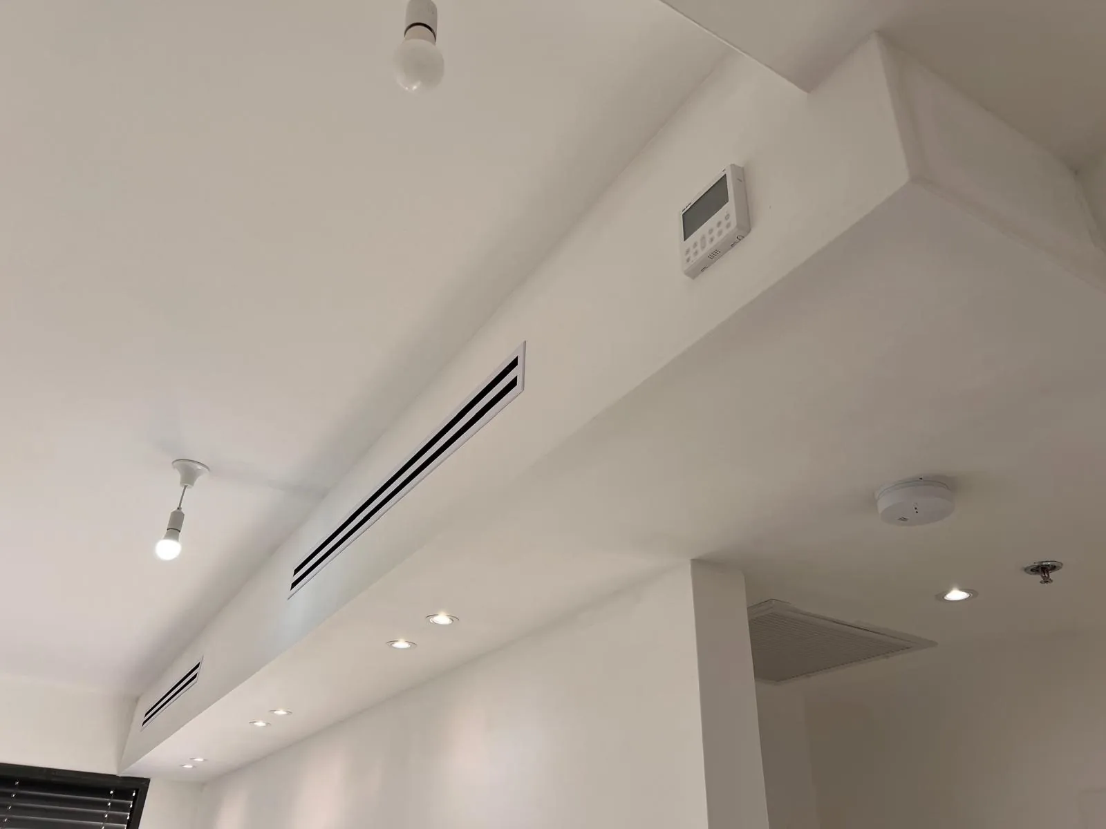 שתי תיבות גבס בתקרה עם יציאות אוויר ליניאריות ושלט הפעלה למזגן